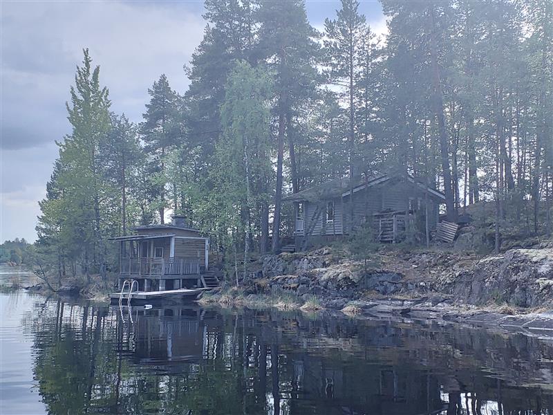 1950-luvulta peräisin oleva saunarakennus ja sen yläpuolelle viime vuosisadan lopulla rakennettu tavanomaisempi mökki.&nbsp;(Dan Ronimus&nbsp;5/2022)