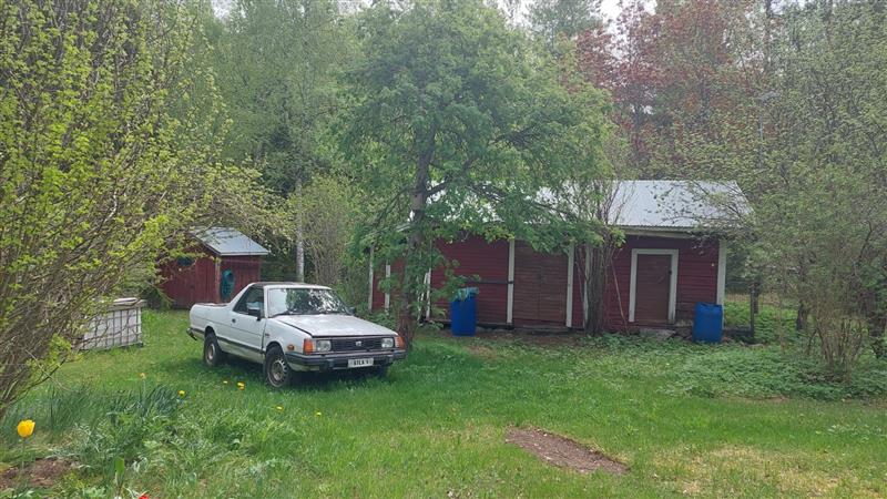 Päärakennuksen pihapiirissä sijaitsevia talousrakennuksia sekä saaren sisäiseen liikkumiseen käytetty vanha lava-auto.&nbsp;(Dan Ronimus&nbsp;5/2022)