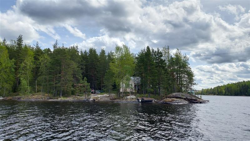 Näkymä kohti kohteen kohtalaisen avointa pihapiiriä ja asuinrakennuksen päätyä.&nbsp;(Dan Ronimus&nbsp;5/2022)