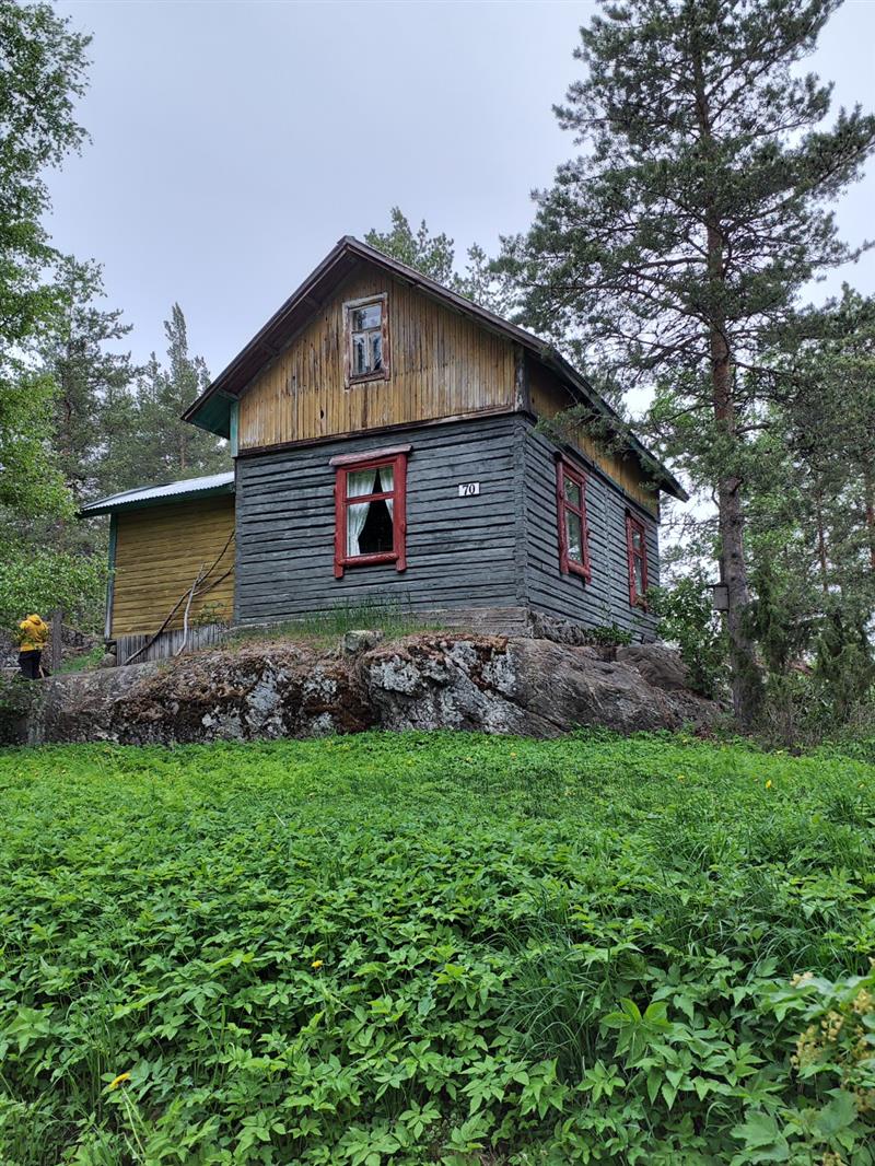 Rannan puolelta katsottuna kallion päälle rakennettu asuinrakennus on huvilamaisempi ja siitä voidaan erottaa jopa kansallisromanttisia piirteitä.&nbsp;(Dan Ronimus&nbsp;5/2022)