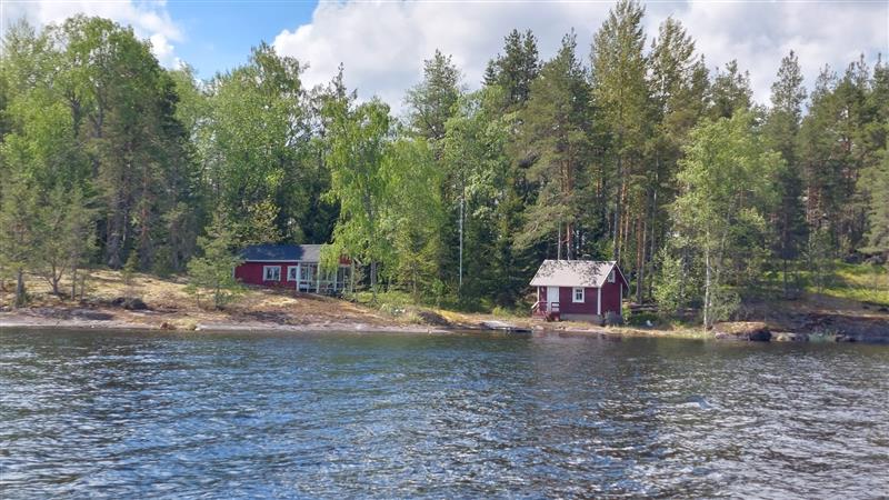 Asuinrakennus vasemmalla ja sauna oikealla reunustavat kohteen edustalle jäävää kalliopoukamaa.&nbsp;(Dan Ronimus&nbsp;5/2022)