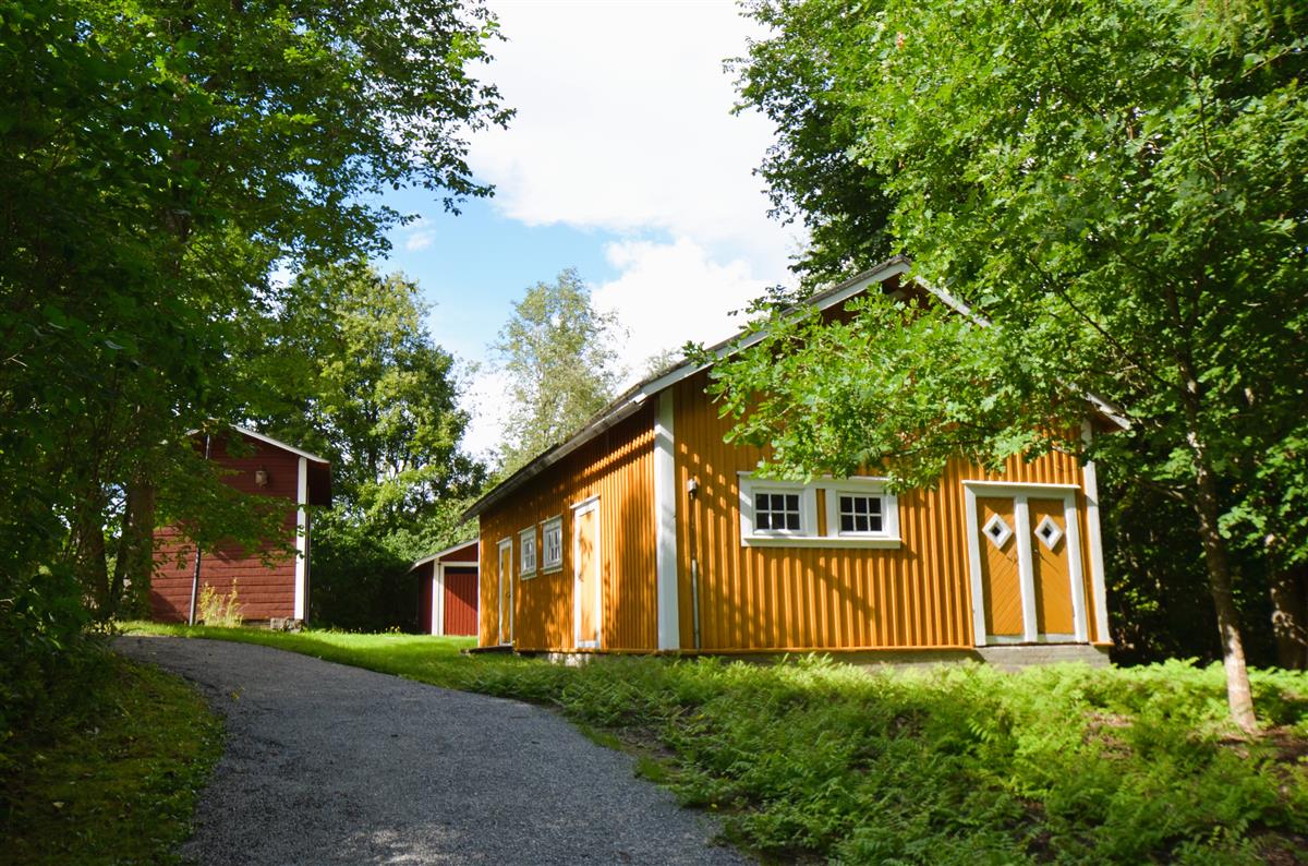 Saimaan kanavan museon navettarakennus etelästä päin kuvattuna. Taustalla aitta ja roskakatos.&nbsp;(Päivi Makkonen&nbsp;2026)