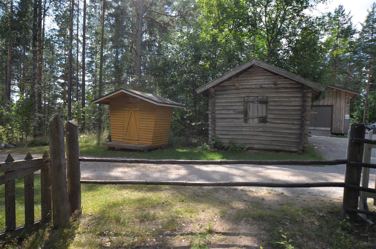 Hakamäen museoalueen aitta koillisesta päin kuvattuna. Vasemmalla maitolaituri, oikealla taustalla huoltorakennus. [Kohteen rakennukseen liitetty kuva]&nbsp;(Päivi Makkonen&nbsp;2025)