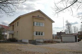 Kuva: Asuinkerrostalo, kerrarissa autotalli. Pihalla lapekattoinen roskakatos.&nbsp;(Minna Pesu&nbsp;3.5.2005)
