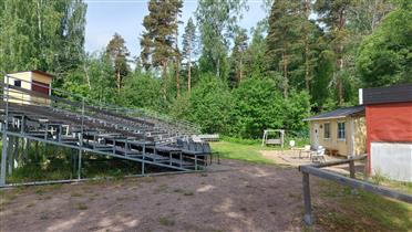 Kuva: Rakennuksen päädyssä vanhan urheilukentän reunalla sijaitseva kesäteatteri.&nbsp;(Dan Ronimus&nbsp;06/2022)